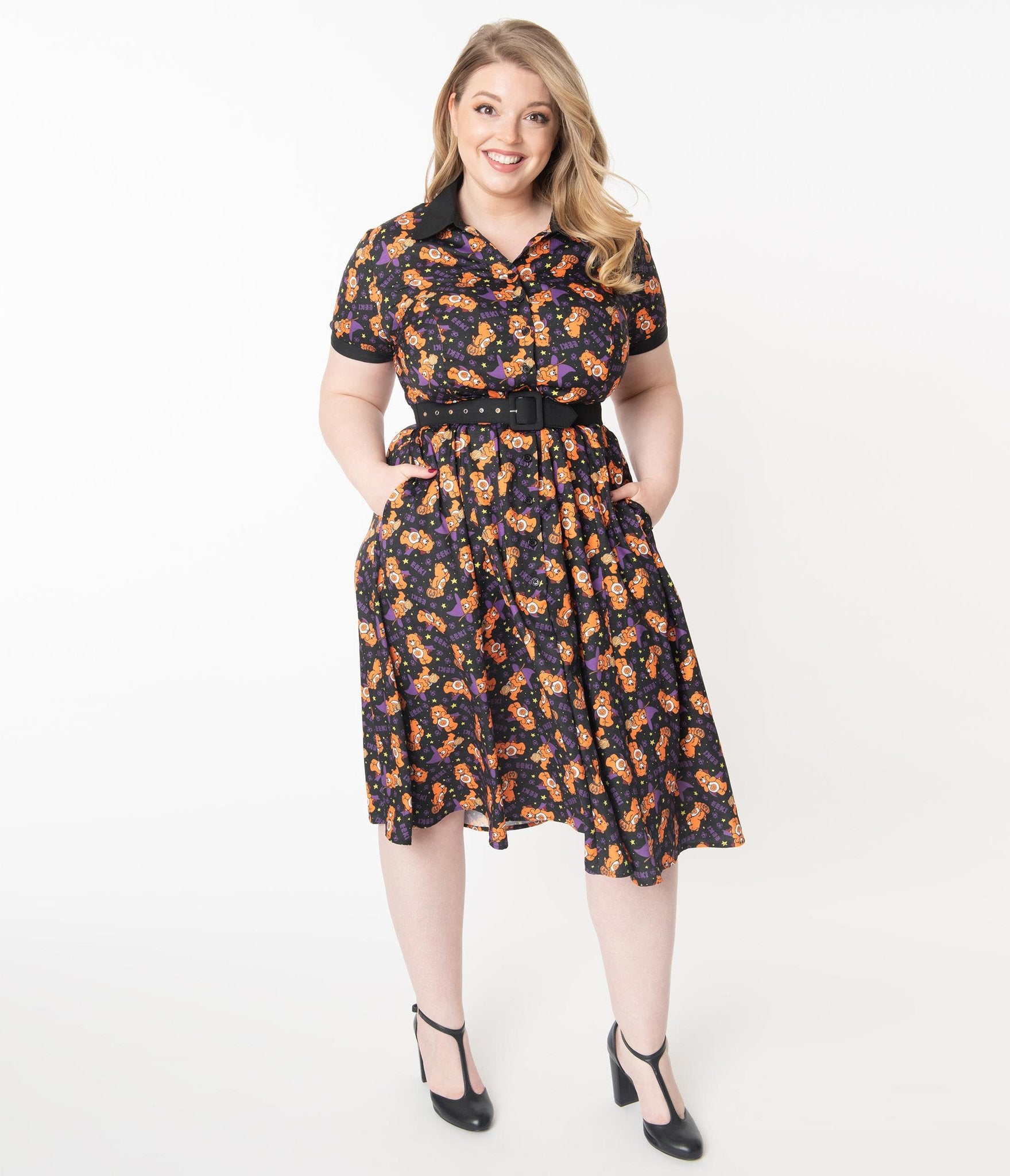 This is a Care Bears Halloween Creepy black swing dress from Unique Vintage and it has an orange trick-r-treat bear with a pumpkin, black belt, black collar and the plus model has blonde hair and is wearing black shoes.