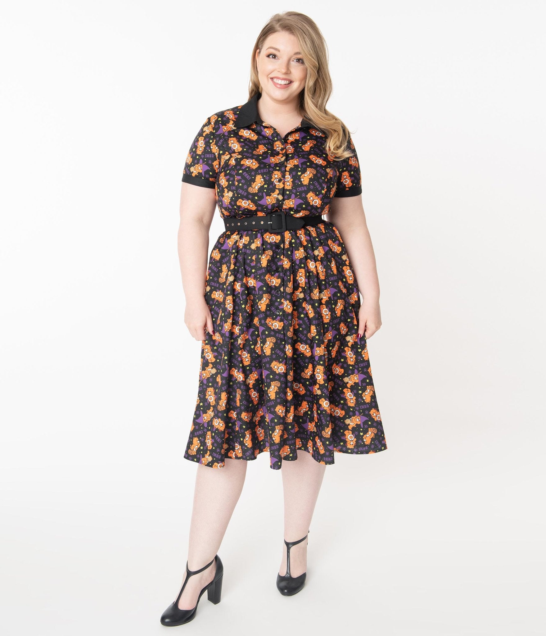 This is a Care Bears Halloween Creepy black swing dress from Unique Vintage and it has an orange trick-r-treat bear with a pumpkin, black belt, black collar and the plus model has blonde hair and is smiling and wearing black shoes.