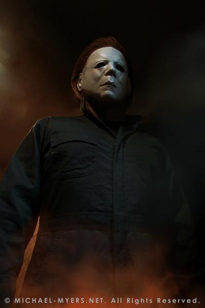 This is a Halloween II Michael Myers mask, that is a white face with brown hair and eye holes and green coveralls and fire.