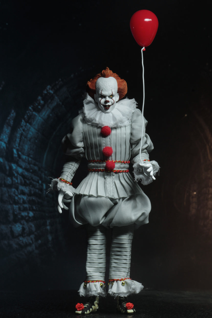 This is an It Movie 2017 Pennywise NECA action figure and he has orange hair, grey suit with red balls, white face, yellow eyes, red balloon and he is in a sewer.