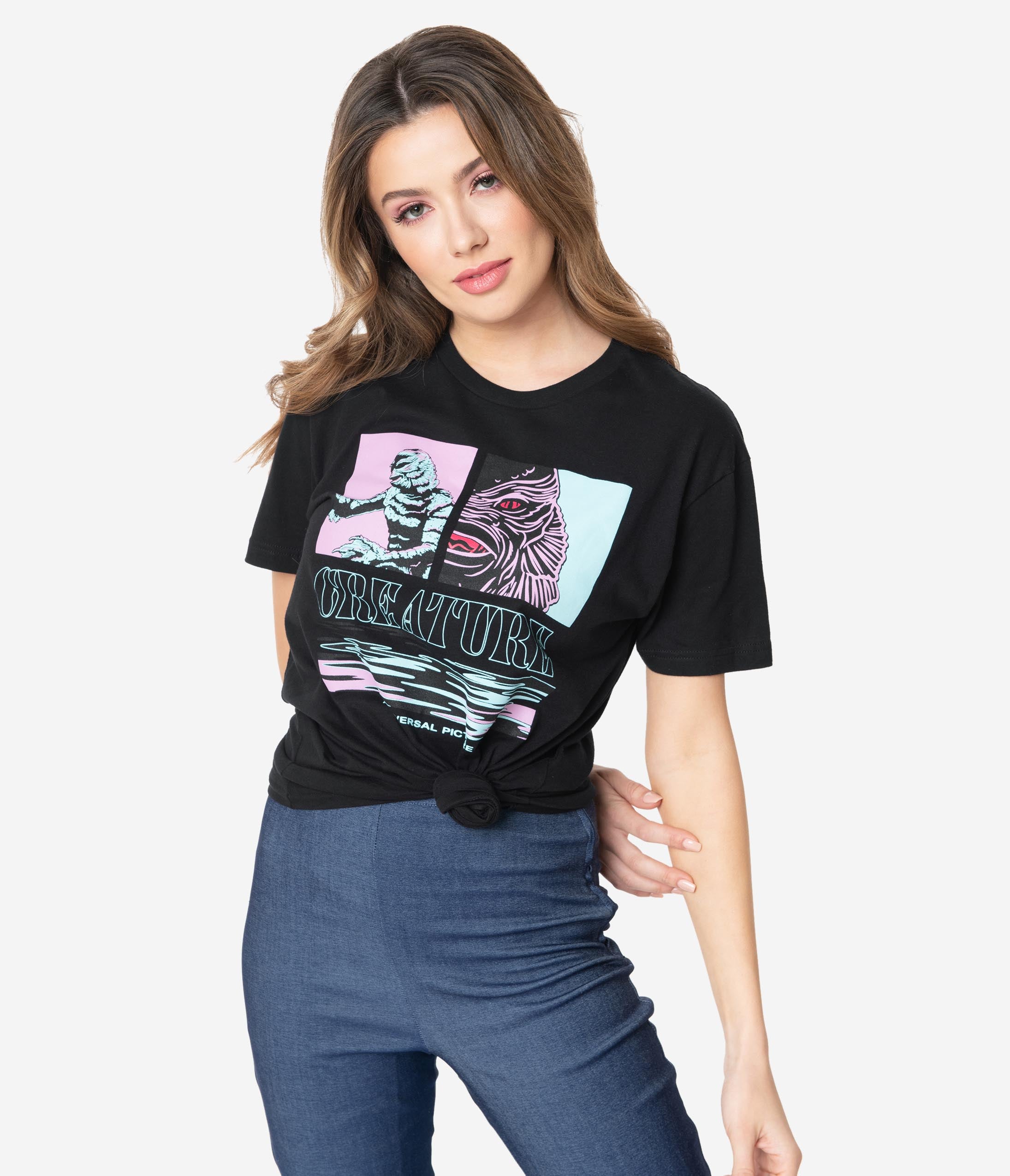 This is a Universal Monsters Creature From the Black Lagoon Unisex Tshirt by Unique Vintage and it is black with pink and blue graphic and creature has gills and scales and the model is a girl with dark blonde hair.