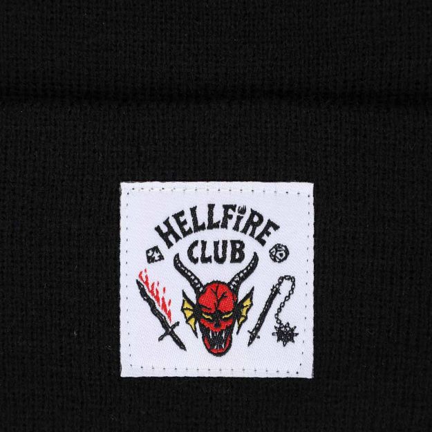 This is a black Stranger Things Hellfire Club beanie with tag that is white with a red devil, flaming sword and spike with spiked ball on the end