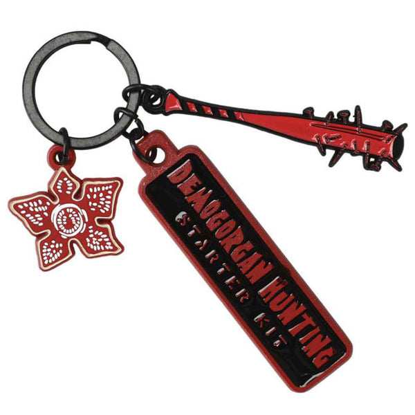 This is a Stranger Things demogorgon hunter keychain that has a demogorgon red face with teeth, a red bat with nails sticking out and a tag that says demogorgon hunting starter kit