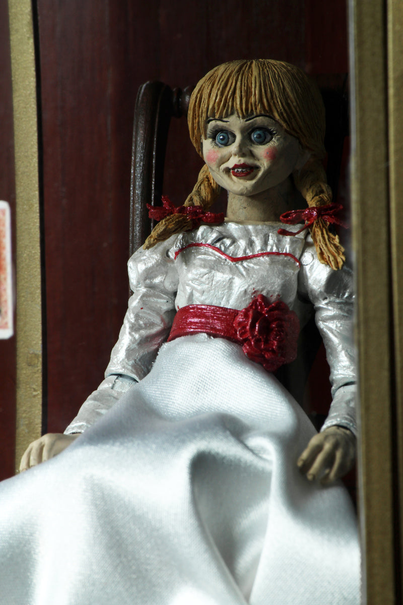 Annabelle NECA action figure from the Conjuring is sitting in a glass display case on a rocking chair and has 2 heads.