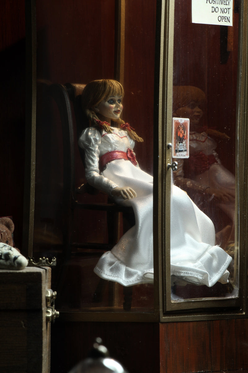 Annabelle NECA action figure from the Conjuring is sitting in a glass display case on a rocking chair and has a note that says miss me