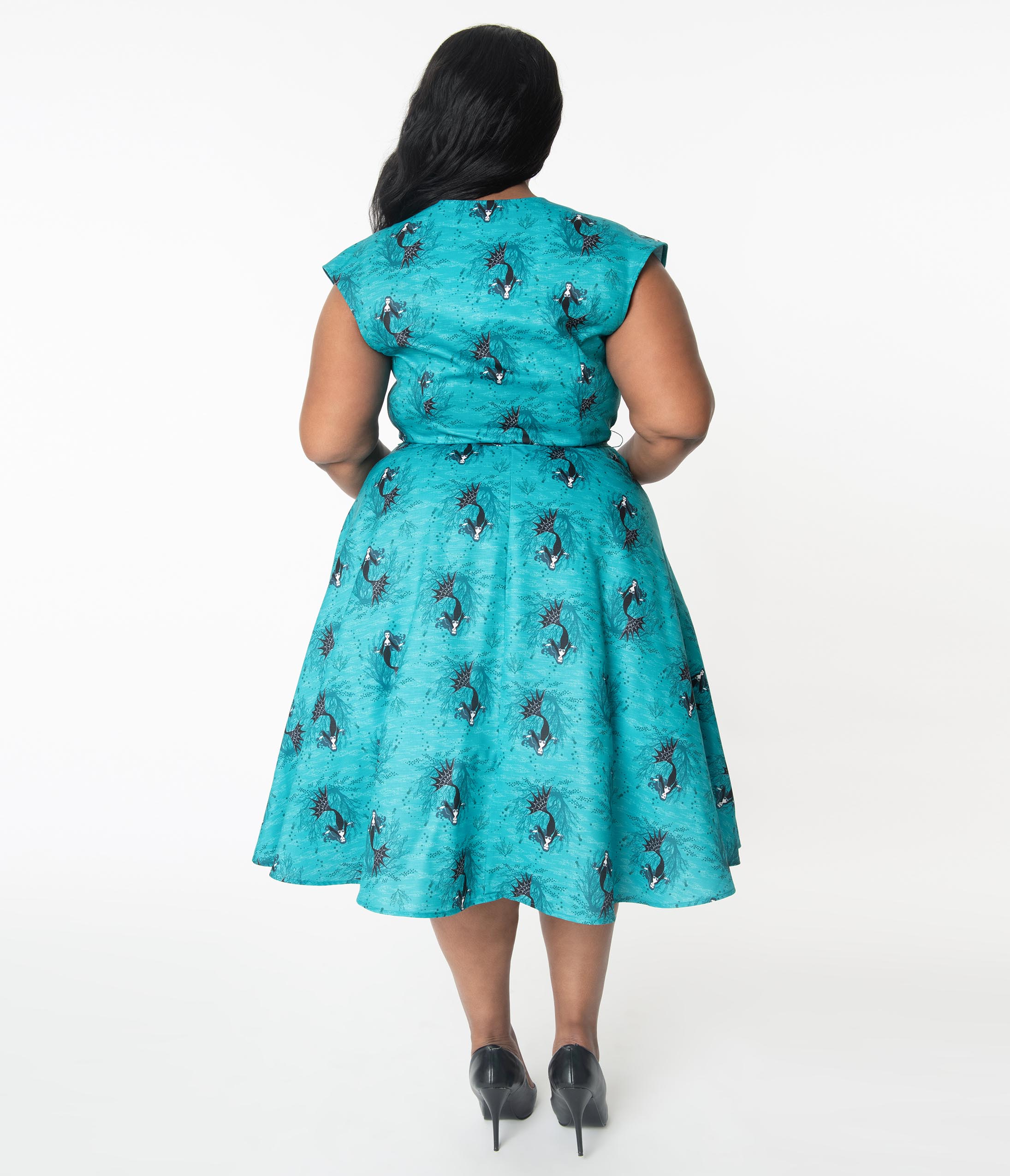 This is an aqua plus size vampire mermaid Unique Vintage dress that has  a belt and the model is wearing black shoes.