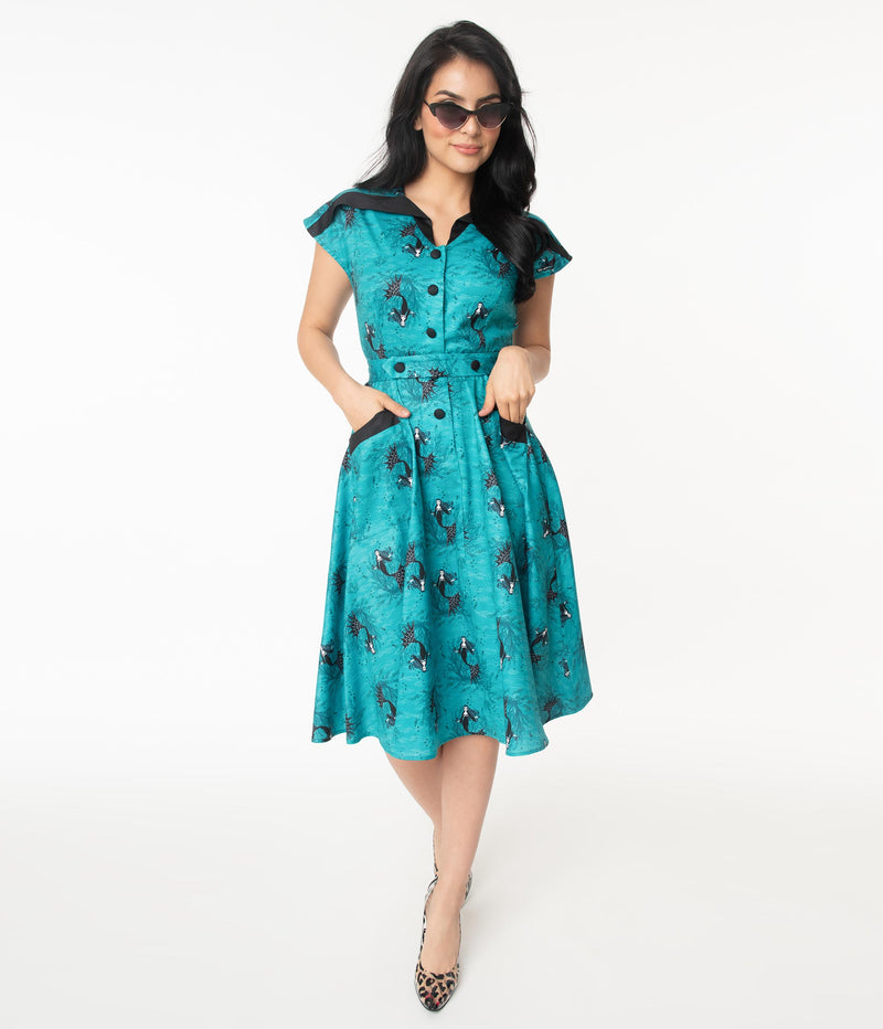 This is an aqua vampire mermaid dress that has black buttons and pockets and the model is wearing leopard shoes and sunglasses.