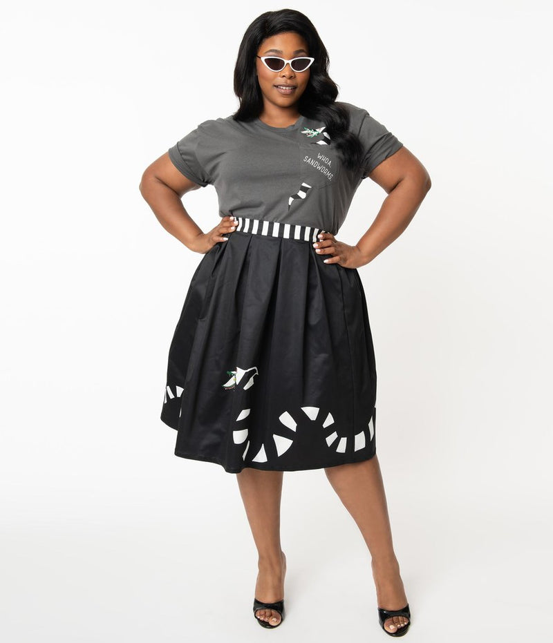 This is a Beetlejuice vintage pinup Sandworm swing skirt from Unique Vintage, that is black with a striped worm and the plus model is wearing a grey shirt and black shoes and sunglasses.