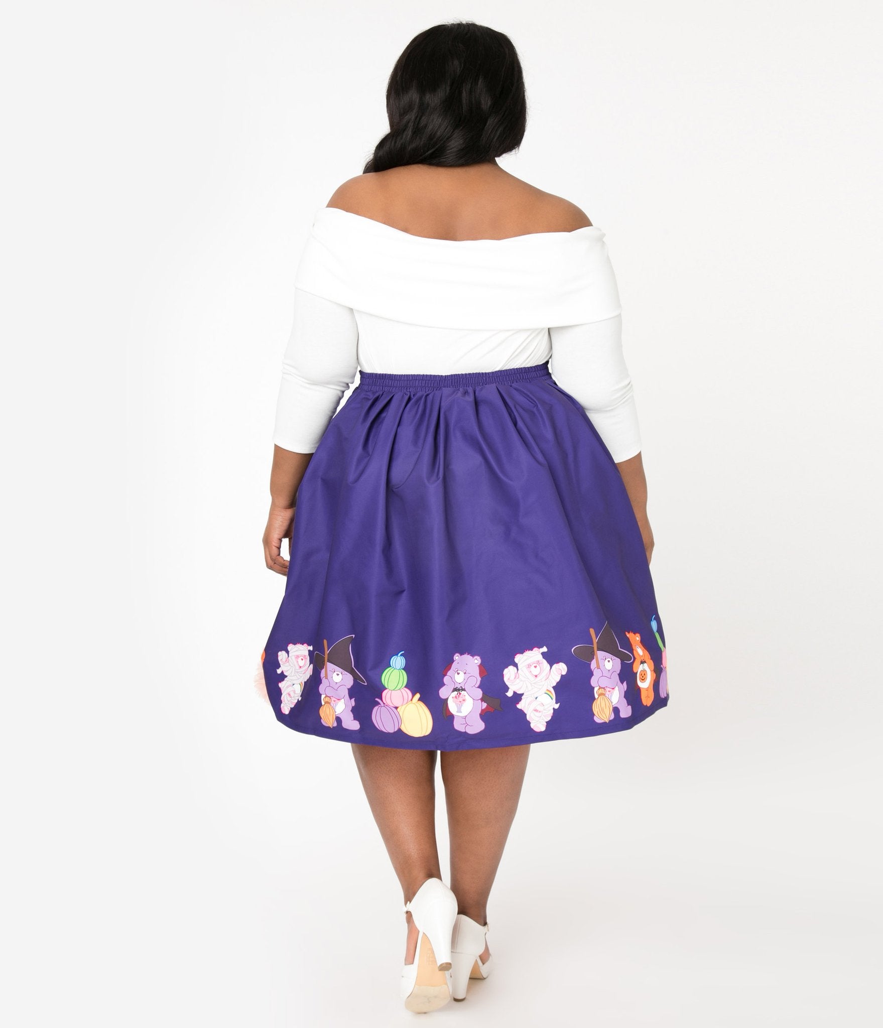 This is a Care Bears halloween purple Jayne swing skirt by Unique Vintage and the plus model is wearing a white shirt and has on white shoes and her dark hair is to the side.