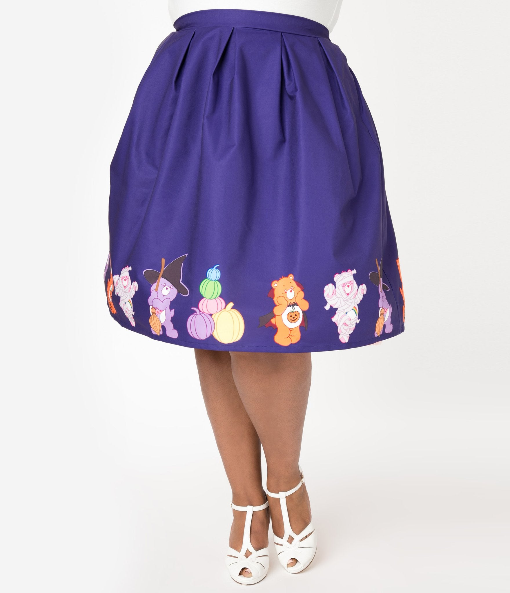 This is a Care Bears halloween purple Jayne swing skirt by Unique Vintage, with pumpkins, witch hats and brooms and the plus model has on white shoes.