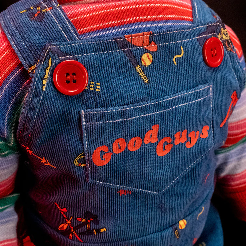 This is a Child's Play 2 Ultimate Chucky doll and he is wearing blue jean overalls, a striped long sleeve shirt and there are red buttons and a baseball, hat and bat