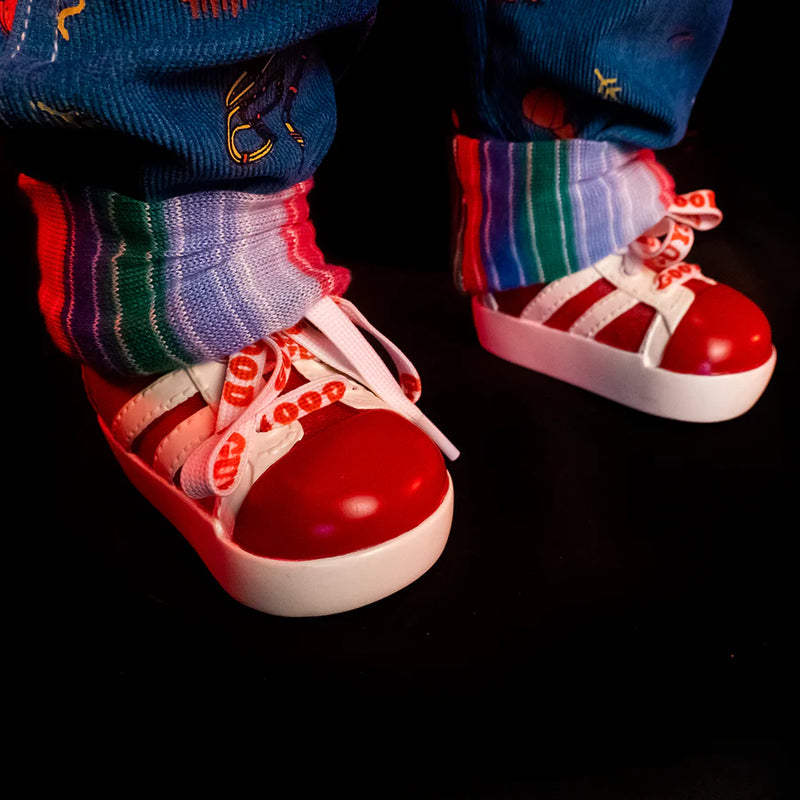 This is a Child's Play 2 Ultimate Chucky doll and he is wearing blue jean overalls, a striped long sleeve shirt, red shoes with white stripes