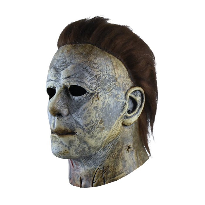 This is a weathered Michael Myers mask bloody edition from Halloween 2018 and it is a grey and brown face and ear with brown hair and black eyes.