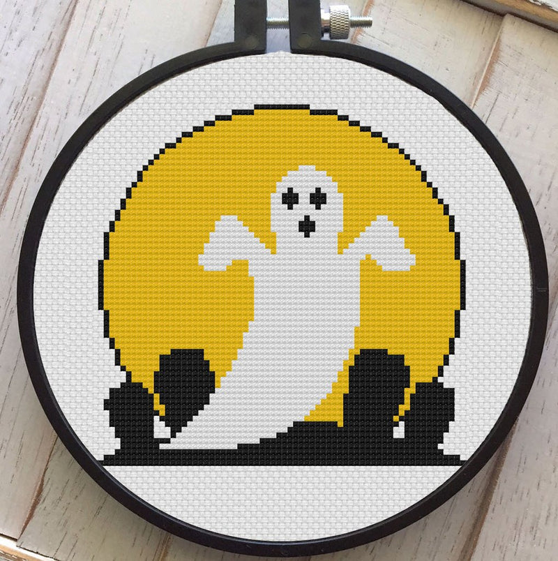 This is a DIY cross stitch kit and it has a white ghost with a yellow moon and he is in front of a cemetery. 