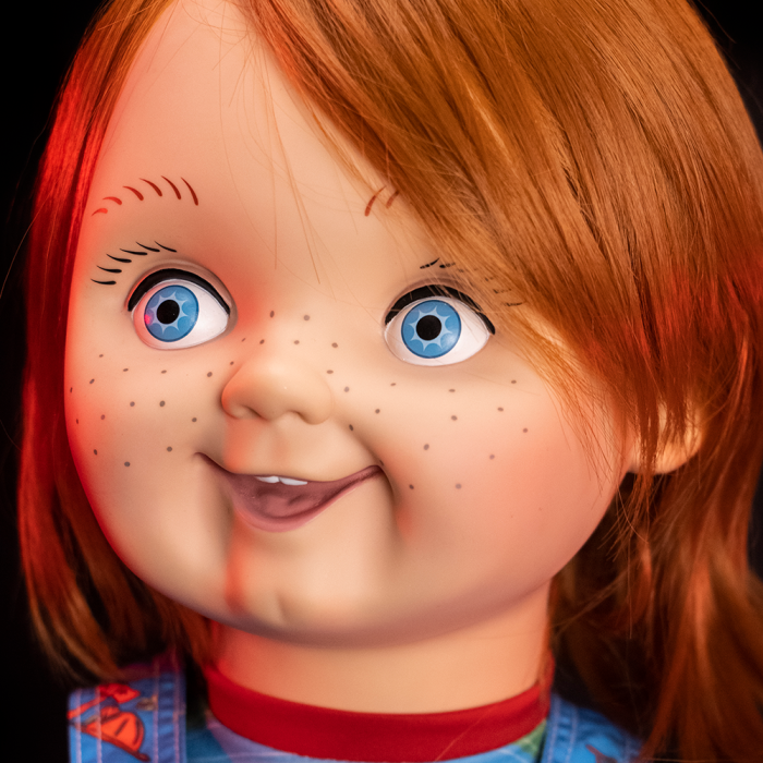 This is a Child's Play Chucky Good Guy doll and he has blue eyes, freckles and orange hair.