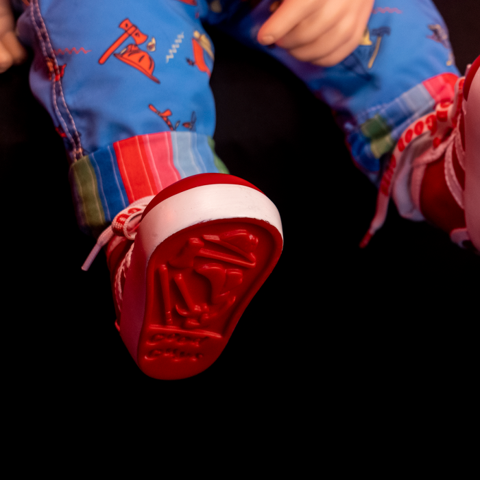 This is a Child's Play Chucky Good Guy doll and he has blue overalls with red buttons and red shoes
