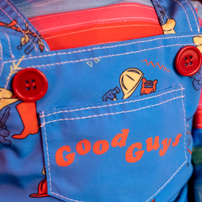 This is a Child's Play Chucky Good Guy doll and he has blue overalls with red buttons.