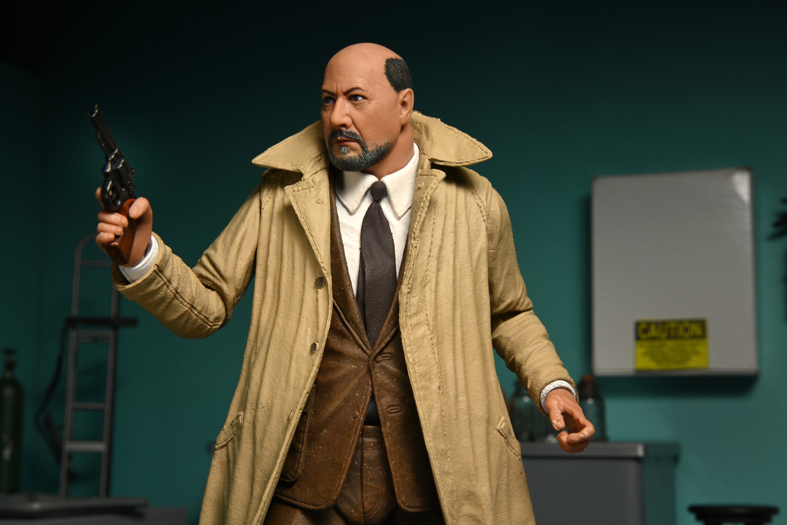 This is a NECA Halloween 2 Michael Myers and Loomis action figure set and Loomis has a tan coat, brown suit, brown tie, holding a gun. 