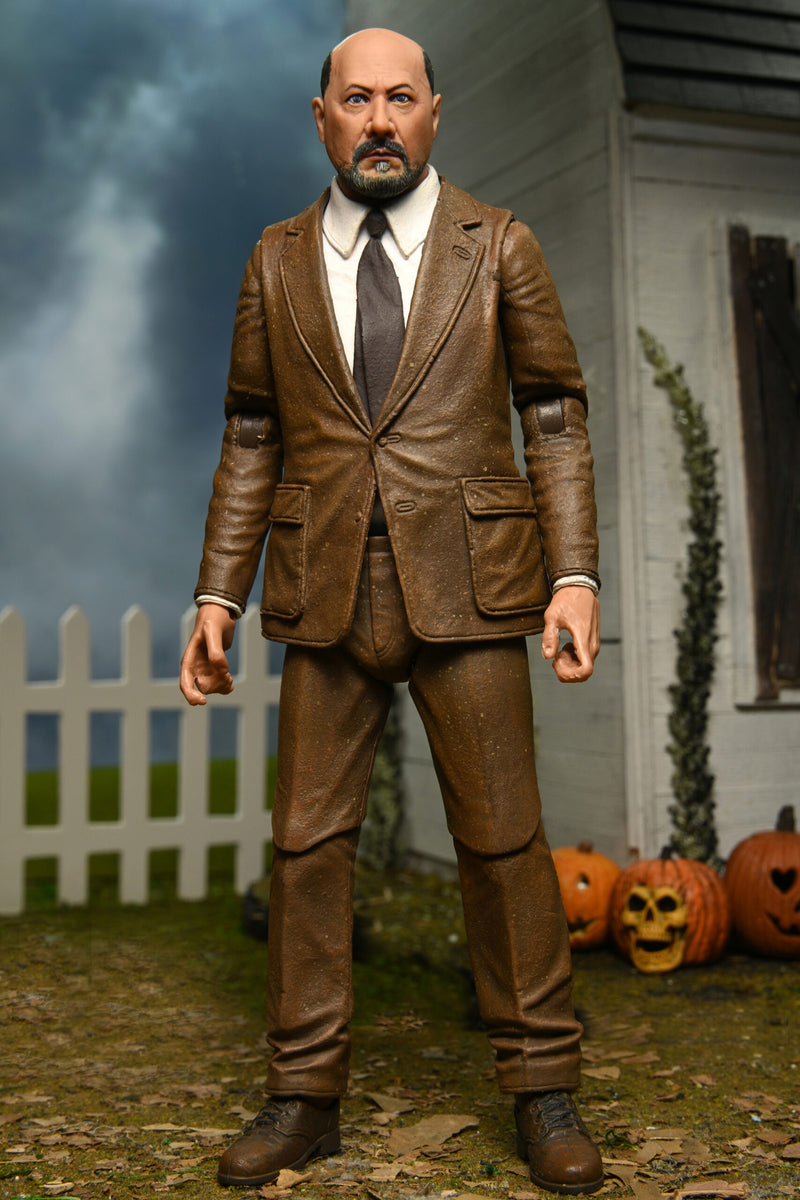 This is a NECA Halloween 2 Michael Myers and Loomis action figure set and Loomis has a brown suit, brown tie and there is an orange pumpkin.