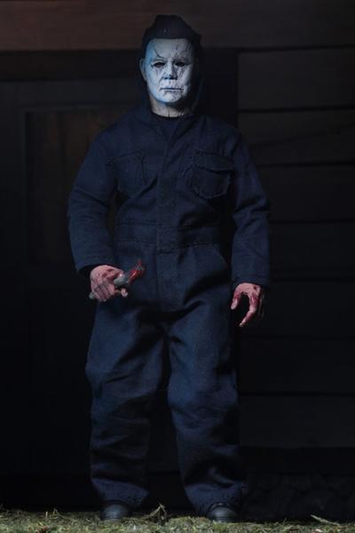 This is a NECA 8" clothed action figure from Halloween 2018 of Michael Myers, who is wearing a grey and weathered mask, grey coveralls, boots and is holding a knife.