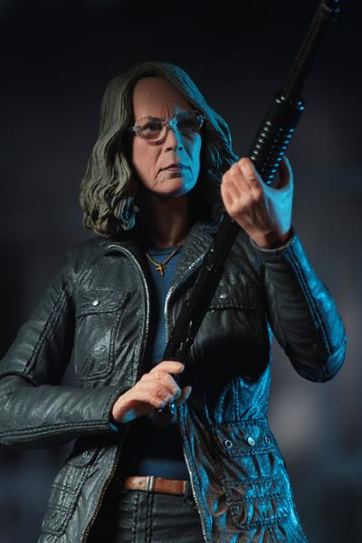 This is a HALLOWEEN 2018 NECA 7" Scale Action Figure Ultimate Laurie Strode and she has grey hair, glasses, a coat and is holding up a rifle.