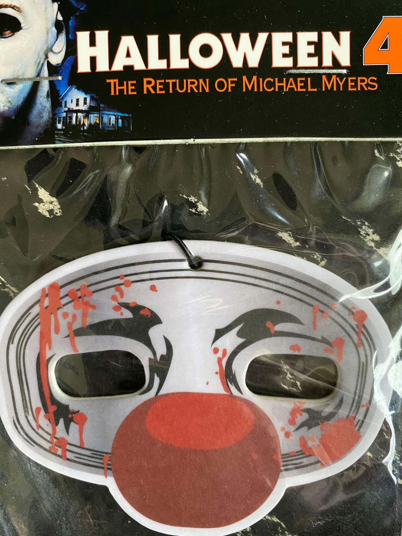 This is a Halloween 4 Return of Michael Myers air freshener that is a grey and silver mask with a red ball nose.