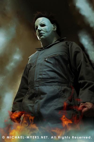 This is a Halloween 6 Curse of Michael Myers mask that is white with brown hair and black eyes and he is wearing coveralls and standing in fire.