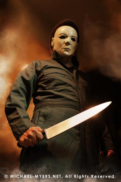 This is a Halloween 8 Resurrection Michael Myers mask that is a white face, brown hair and black eyes with coveralls, a silver and shiny knife, with fire.