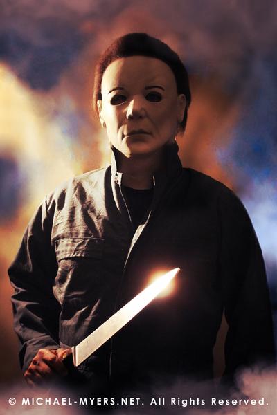 This is a Halloween 8 Resurrection Michael Myers mask that is a white face, brown hair and black eyes with coveralls, a silver and shiny knife and white smoke.
