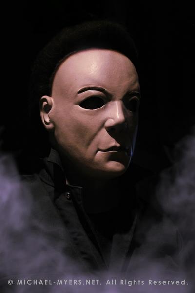 This is a Halloween 8 Resurrection Michael Myers mask that is a white face, brown hair and black eyes with coveralls and white smoke.