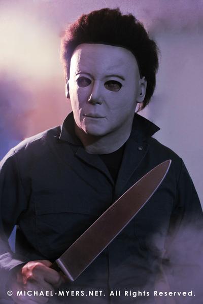 This is a Michael Myers Halloween H20 Mask that is white with brown hair and he is wearing green coveralls and holding a knife.
