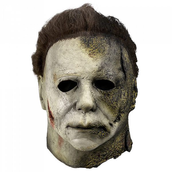 This is a Halloween Kills Michael Myers mask and he has a white face that has black burns and his brown hair is burnt.