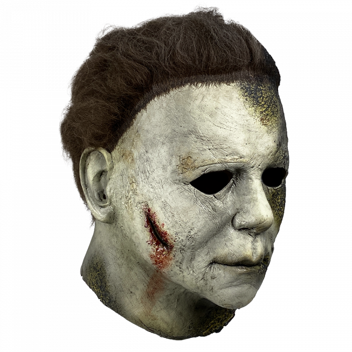 This is a Halloween Kills Michael Myers mask and he has a white face that has black burns and his brown hair is burnt and he has a bloody cut.