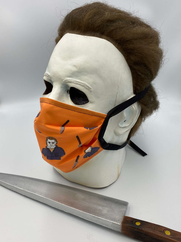 This is a Halloween Michael Myers protective cotton face mask and it is orange, he has a white mask and there is a bloody knife.
