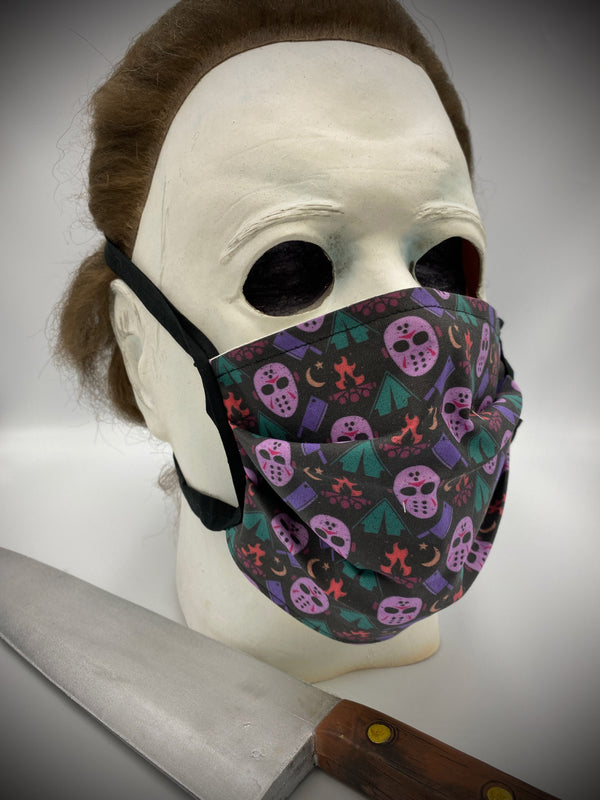 This is a black protective face mask with black ties and it is a Friday the 13th Jason Voorhees pink hockey mask and a purple butcher knife, tents and a campfire, worn by Michael Myers.