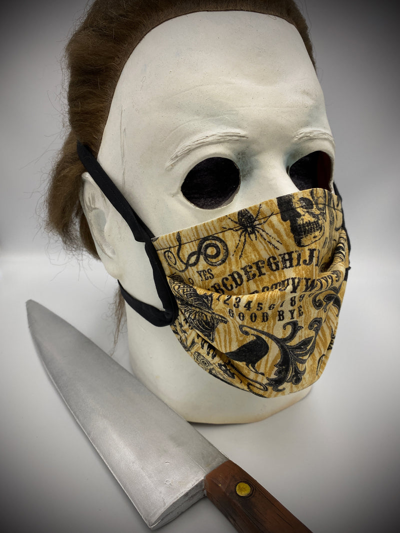 This is a brown protective face mask with black ties and it has a ouija board, skeleton, moth, bugs and cages., worn by Michael Myers
