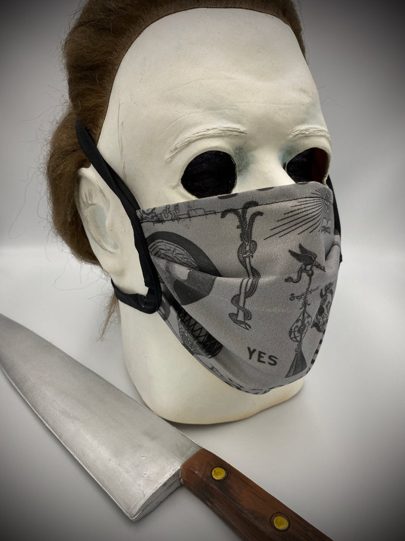 This is a black protective face mask with black ties and it has a ouija board, skeleton, octopus, skulls and bottles, worn by Michael Myers.