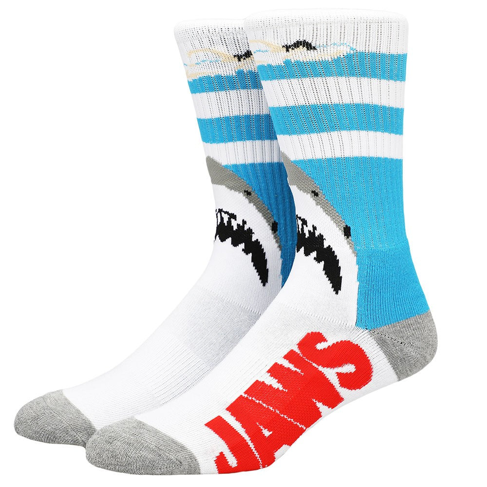 This is a pair of Jaws crew socks and there is a girl swimming in the water and a shark below her.