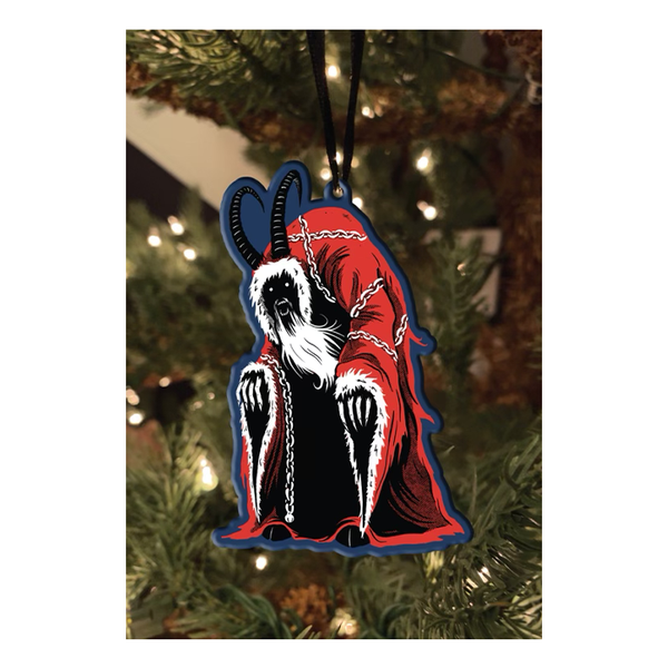 This is a Krampus metal ornament and he is wearing a red robe with white furry trim, chains and he has horns.