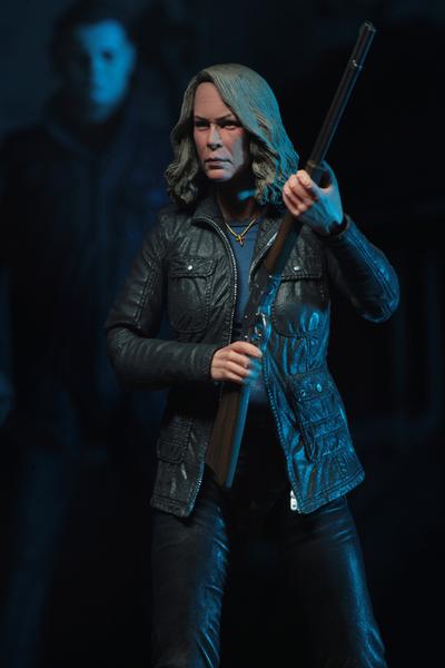 This is a HALLOWEEN 2018 NECA 7" Scale Action Figure Ultimate Laurie Strode and she has grey hair, glasses, a coat and is holding up a rifle with Michael Myers behind her.