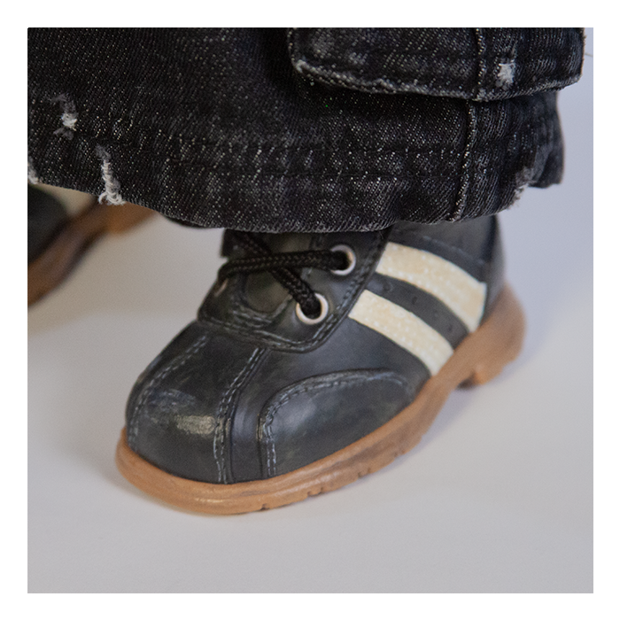 This is a Seed of Chucky Glen life size doll and he has black shoes with white stripes and black jeans.