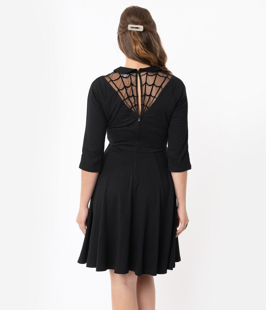 This is a black Unique Vintage flare dress that has a spiderweb neck, Peter Pan collar, 3/4 sleeves and the model is wearing a silver hair clip.