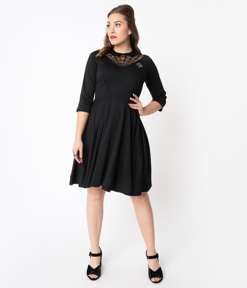 This is a black Unique Vintage flare dress that has a spiderweb neck, Peter Pan collar, 3/4 sleeves and the model is wearing black shoes.