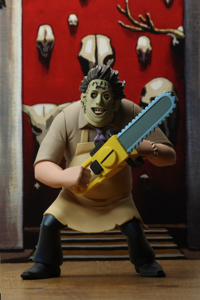 Leatherface is standing in front of a red wall, while wearing a yellow apron and holding a yellow chainsaw.