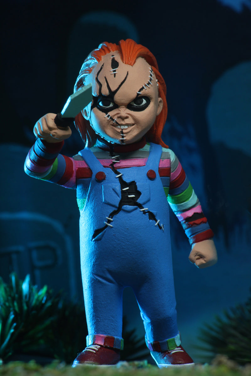 Chucky NECA action figure is wearing a striped shirt with coveralls, holding a knife and has scars on his face.