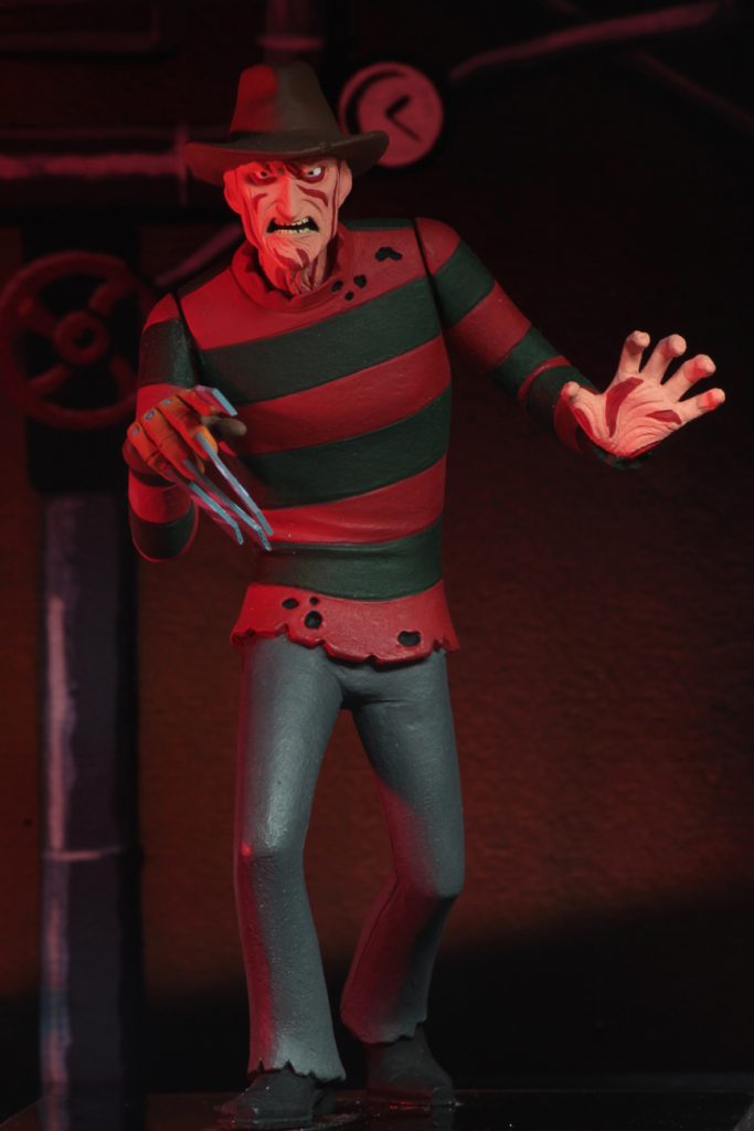 This is a NECA Toony Terror action figure of Nightmare On Elm Street Freddy Krueger, who is wearing a brown hat, red and green sweater and grey pants.