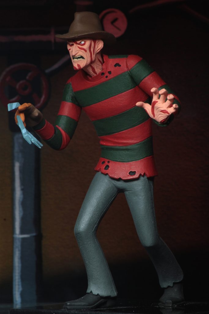 This is a A Nightmare On Elm Street Freddy Krueger posable NECA 6" action figure, who has a glove with blades and is wearing a red and green striped sweater, brown hat and grey pants.