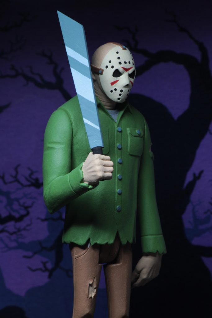 This is a Friday the 13th Jason Voorhees posable NECA 6" action figure, who is holding a machete and wearing a green shirt, brown pants and a hockey mask.