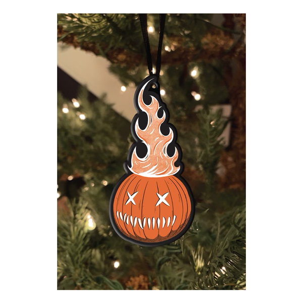 This is a Trick 'R Treat Same bitten lollipop metal ornament that is hanging from a black ribbon and has an orange pumpkin, with x eyes and fire coming out of it.