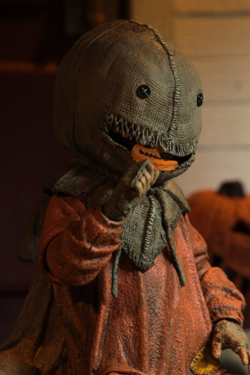 This is a Trick R Treat Sam NECA 7" ultimate action figure and he has a burlap mask, an orange suit, gloves and an orange lollipop.